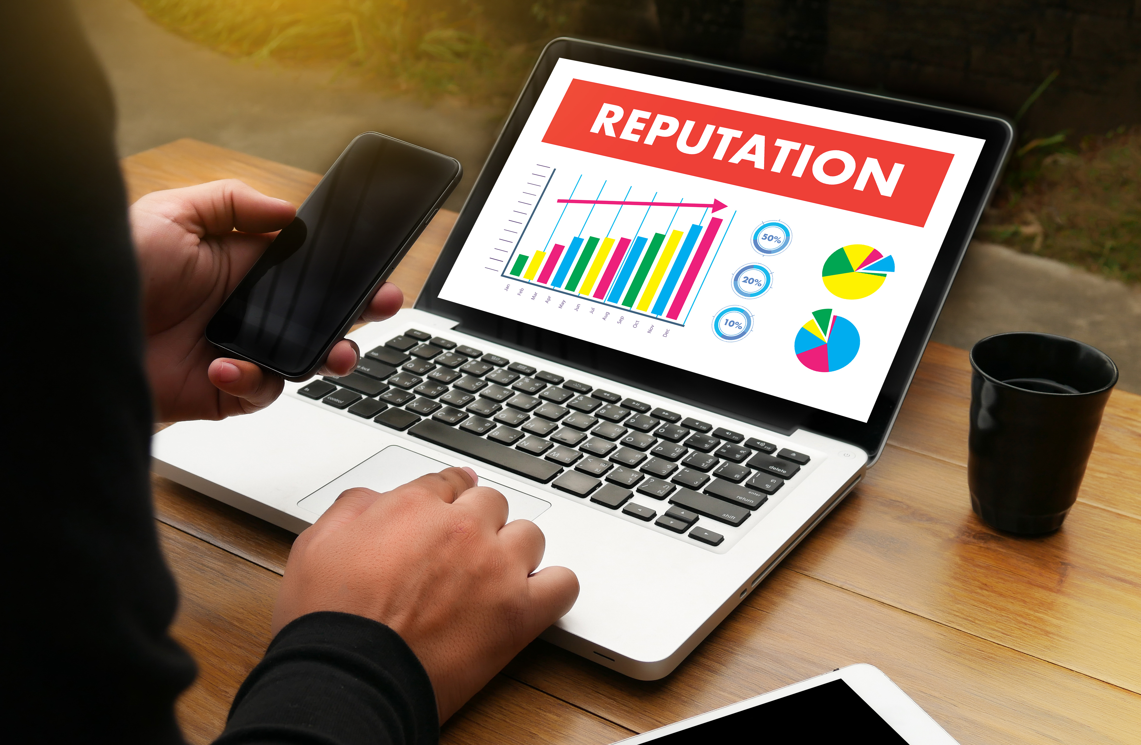 A person working on a laptop displaying a graph with increasing values titled REPUTATION.